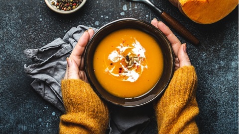 vrouw houdt handen om kom butternut pompoensoep